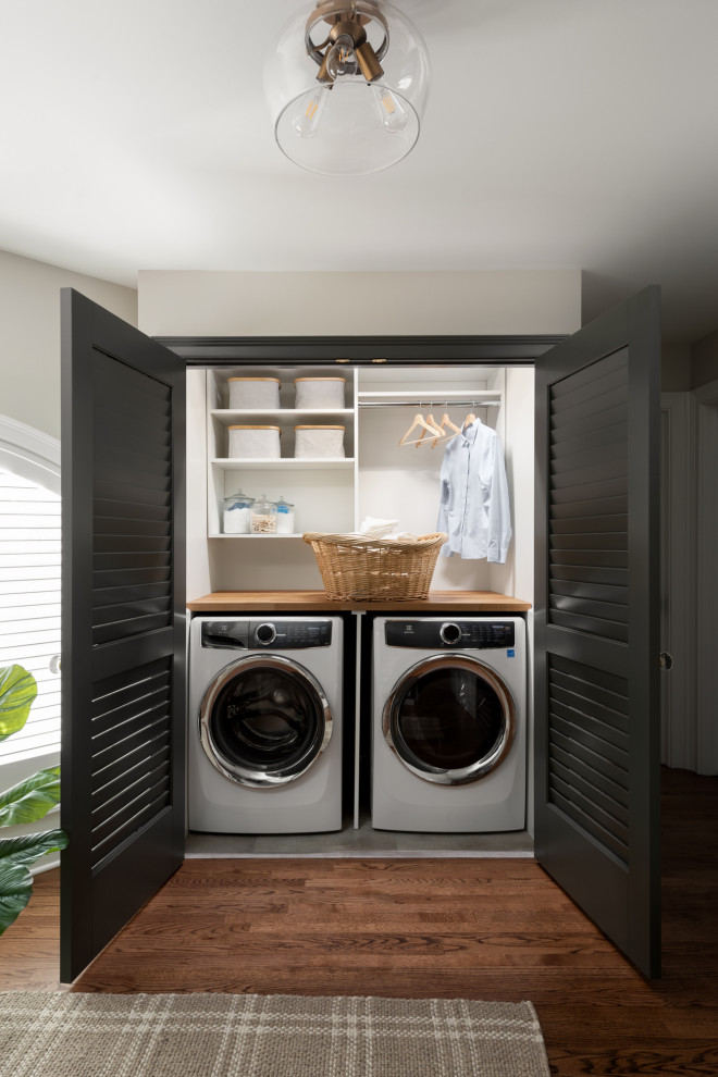 Immagine di un piccolo ripostiglio-lavanderia tradizionale con top in legno, pavimento in legno massello medio e lavatrice e asciugatrice affiancate