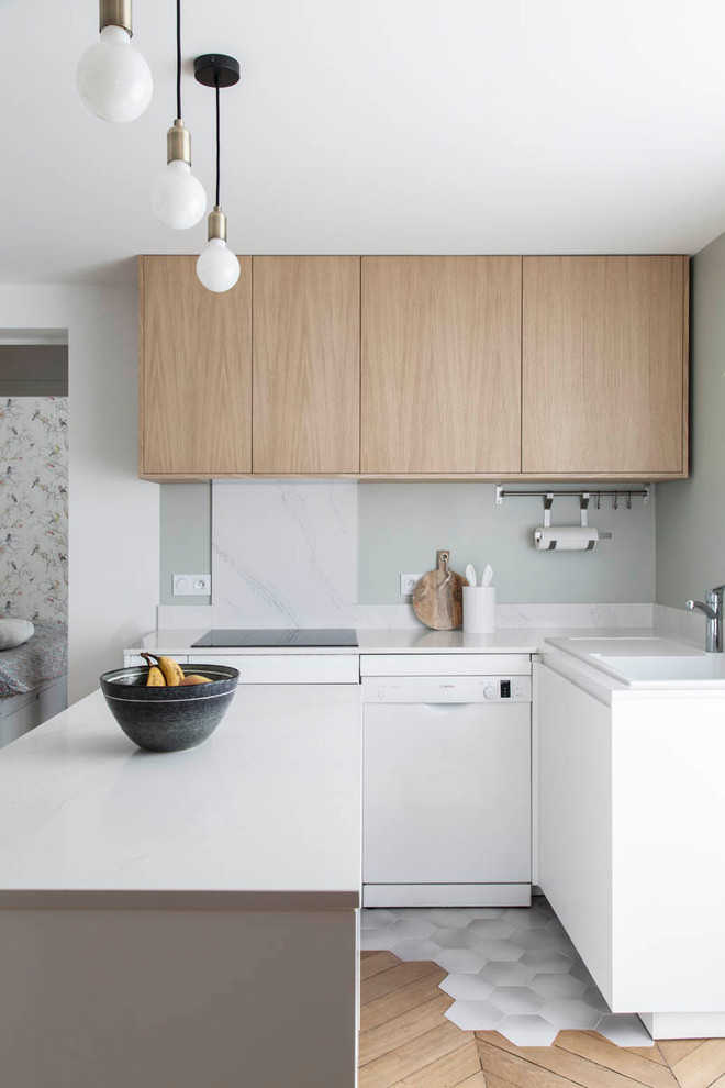Inspiration for a small contemporary u-shaped kitchen in Paris with a drop-in sink, flat-panel cabinets, light wood cabinets, white splashback, stone slab splashback, white appliances, a peninsula and white benchtop.