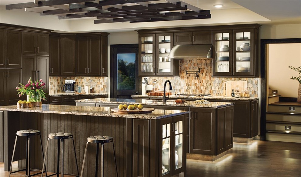 Large contemporary l-shaped kitchen pantry in Detroit with an undermount sink, raised-panel cabinets, white cabinets, wood benchtops, stainless steel appliances, brown splashback, glass tile splashback, dark hardwood floors, multiple islands and brown floor.