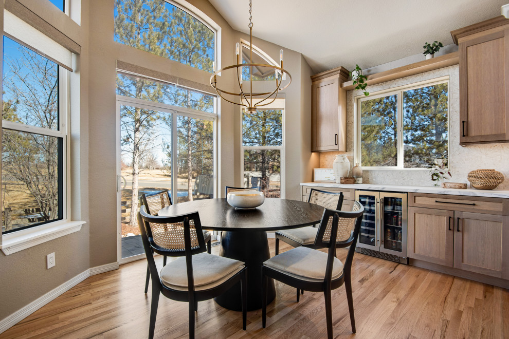 Photo of an expansive traditional l-shaped kitchen/diner in Denver with a belfast sink, shaker cabinets, white cabinets, engineered stone countertops, white splashback, engineered quartz splashback, stainless steel appliances, medium hardwood flooring, an island, brown floors and white worktops.