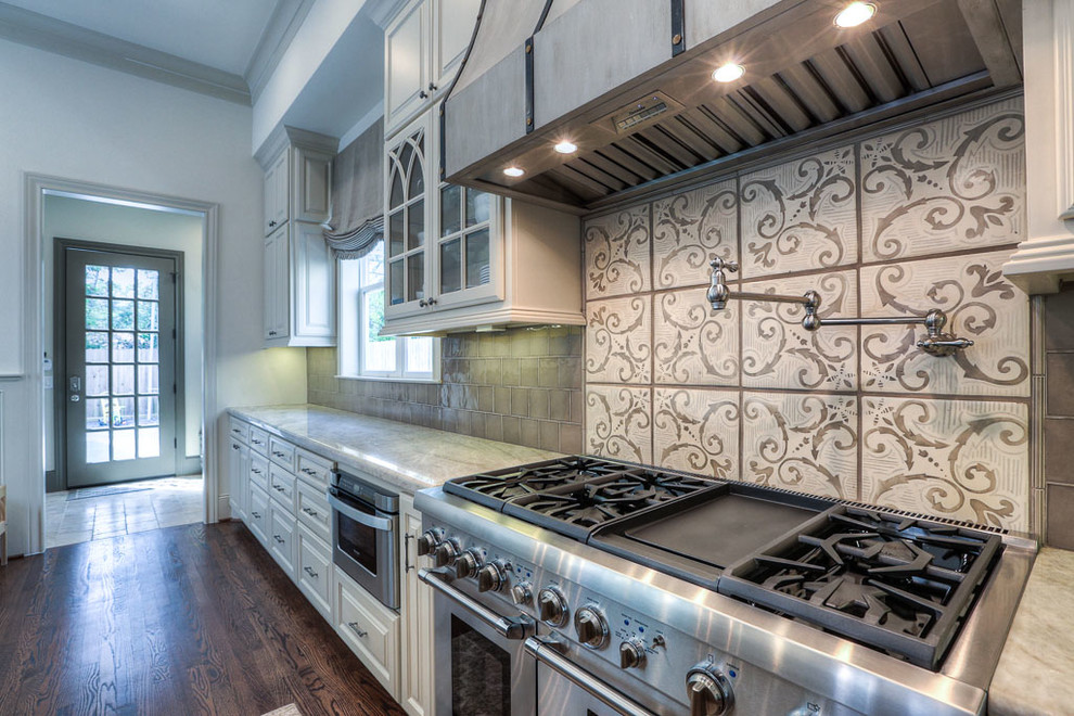 Large traditional l-shaped eat-in kitchen in Houston with a double-bowl sink, raised-panel cabinets, white cabinets, quartzite benchtops, grey splashback, glass tile splashback, stainless steel appliances, dark hardwood floors and with island.