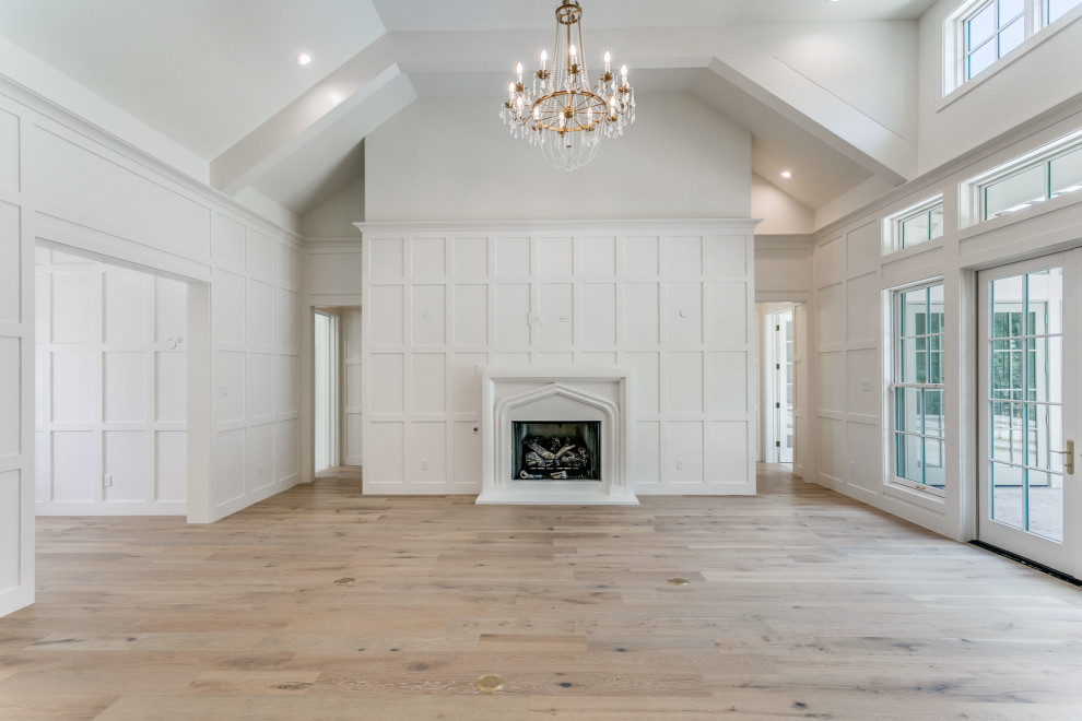 Cette image montre un grand salon avec un mur blanc, parquet clair et une cheminée standard.