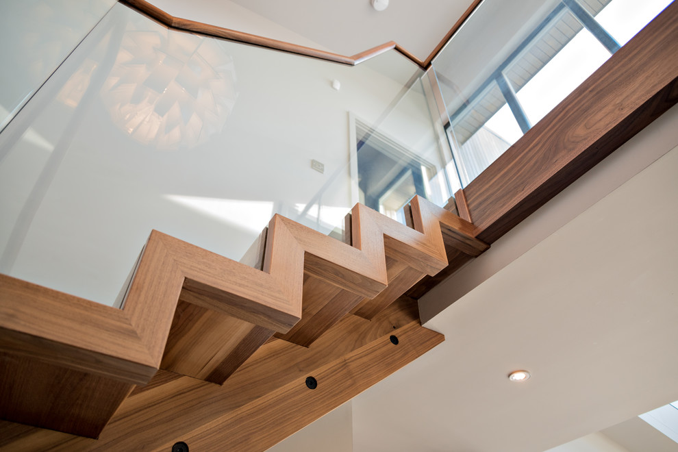 Inspiration for a large contemporary wood floating staircase in Cambridgeshire with wood risers and glass railing.