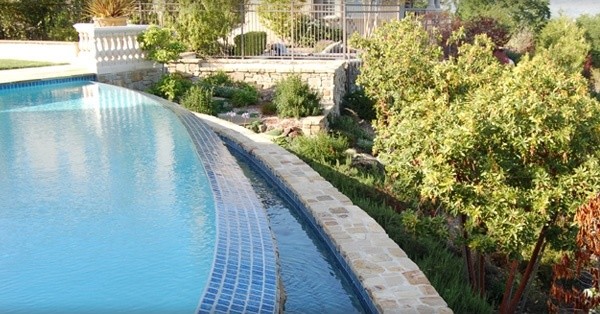 Photo of a mid-sized mediterranean backyard round infinity pool in San Francisco with natural stone pavers.