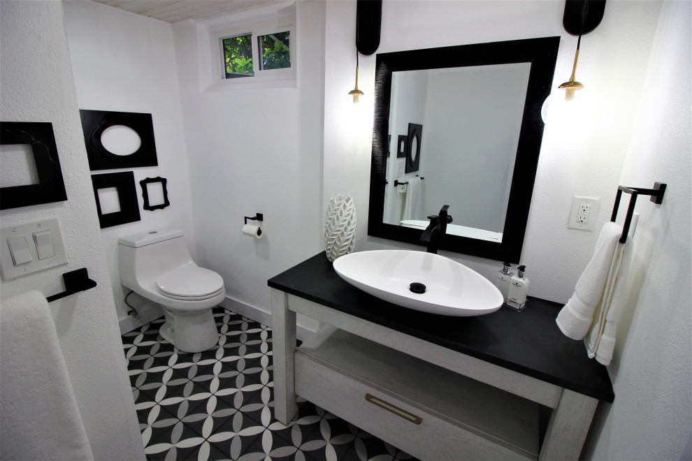 Design ideas for a small transitional bathroom in Portland with open cabinets, white cabinets, an alcove shower, a one-piece toilet, white tile, subway tile, white walls, ceramic floors, a vessel sink, engineered quartz benchtops, black floor, a sliding shower screen, black benchtops, a single vanity and a freestanding vanity.
