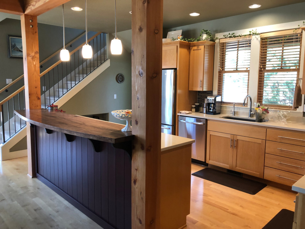 Example of a mid-sized transitional l-shaped medium tone wood floor open concept kitchen design in Portland with an undermount sink, flat-panel cabinets, light wood cabinets, quartz countertops, multicolored backsplash, ceramic backsplash, stainless steel appliances, an island and white countertops