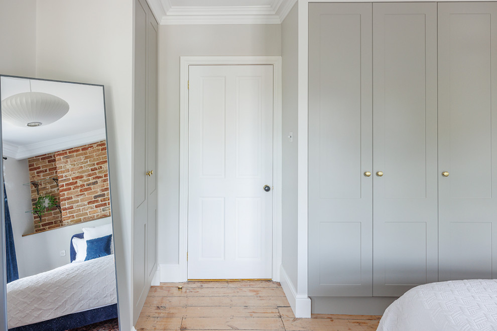 Réalisation d'une chambre parentale minimaliste de taille moyenne avec un mur gris et un sol en bois brun.