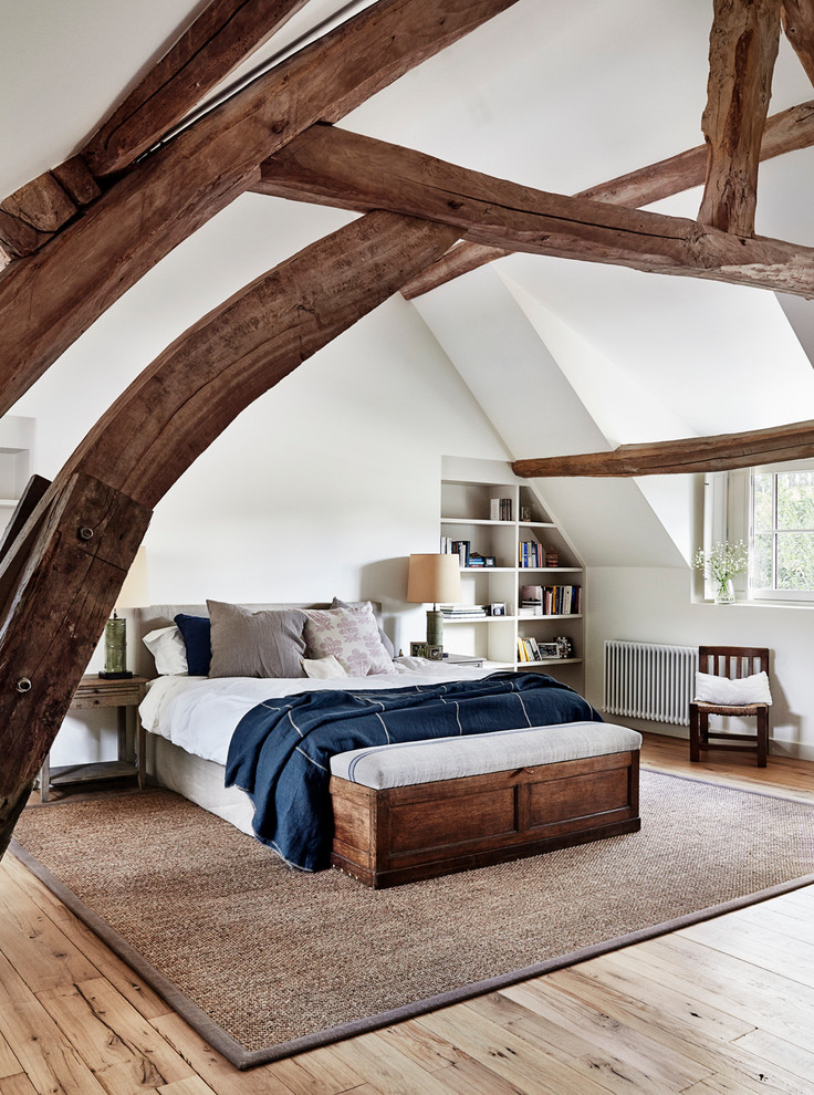 This is an example of a large country bedroom in Paris with white walls and light hardwood floors.