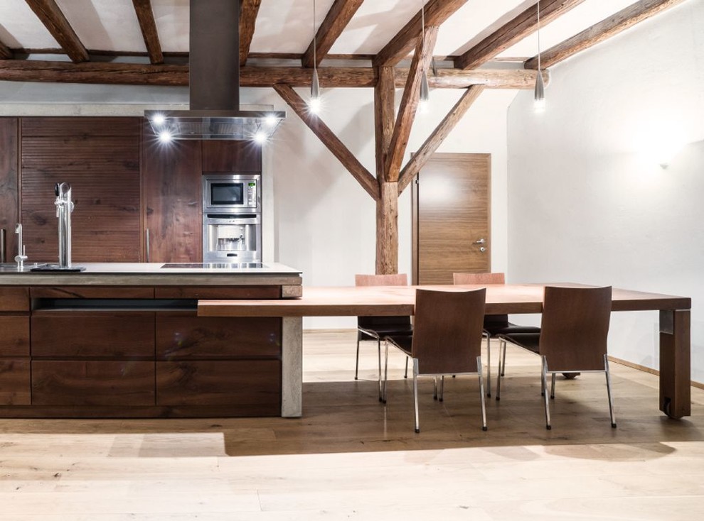 Photo of a large contemporary eat-in kitchen in Munich with flat-panel cabinets, dark wood cabinets, stainless steel appliances, light hardwood floors, a peninsula and concrete benchtops.