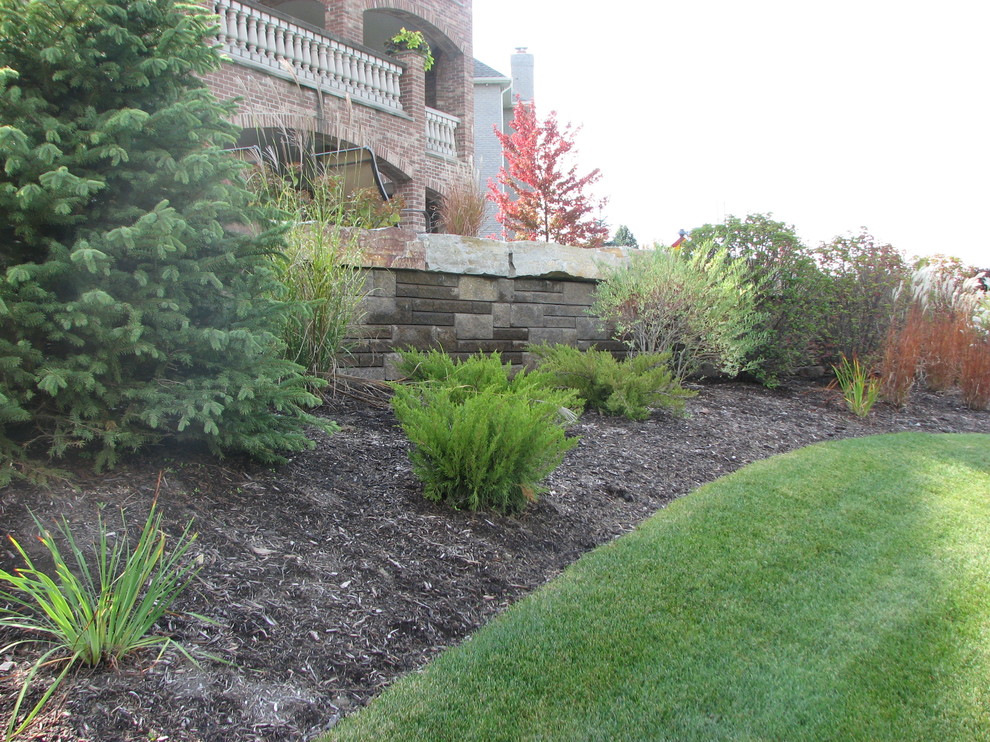 Inspiration for a mid-sized transitional backyard full sun garden in Chicago with a retaining wall and natural stone pavers.