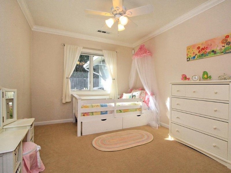 This is an example of a small beach style toddler room for girls in San Francisco with beige walls and carpet.