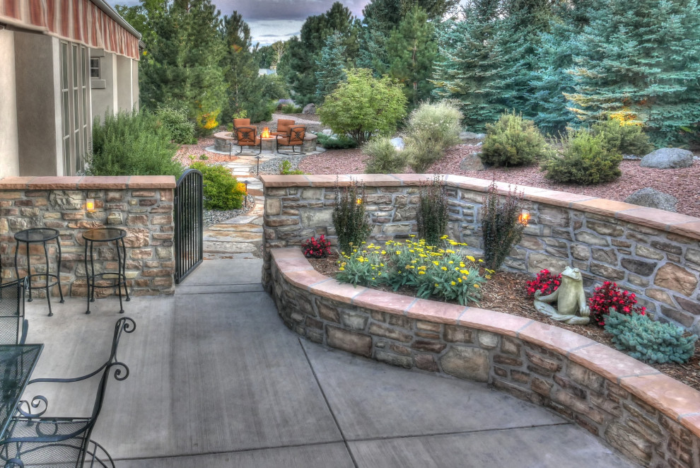 Photo of a medium sized traditional back patio in Denver with a potted garden, concrete slabs and an awning.