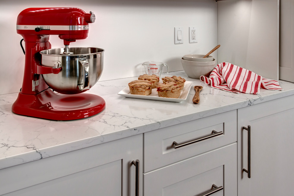 Home design - mid-sized contemporary galley medium tone wood floor home design idea in Seattle with an undermount sink, shaker cabinets, quartz countertops, gray backsplash, porcelain backsplash, stainless steel appliances, an island and white cabinets