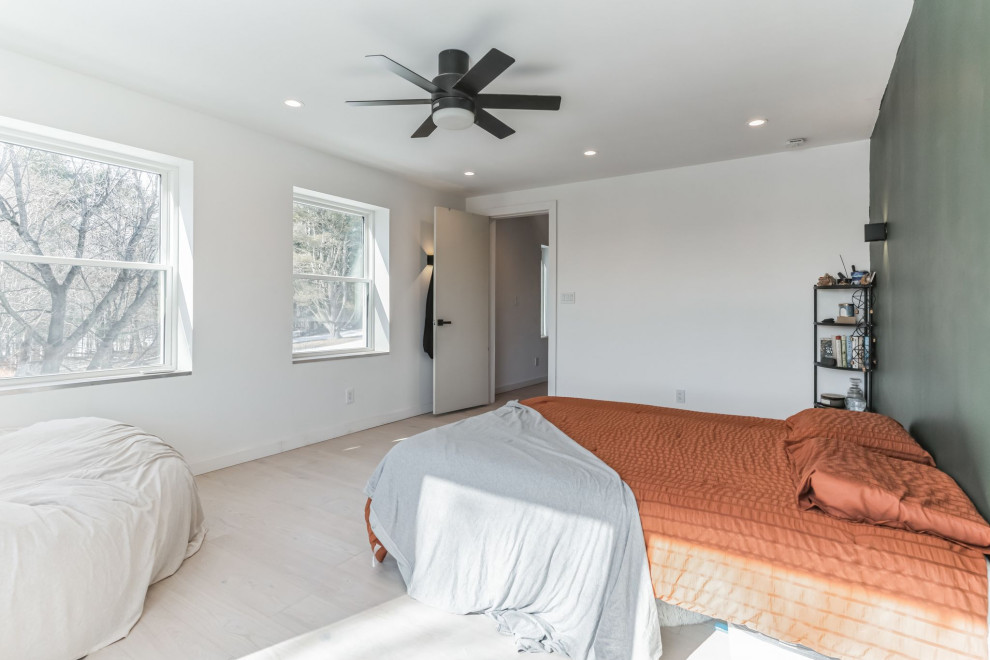 This is an example of a mid-sized contemporary loft-style bedroom in Portland Maine with white walls, vinyl floors, no fireplace, beige floor and vaulted.