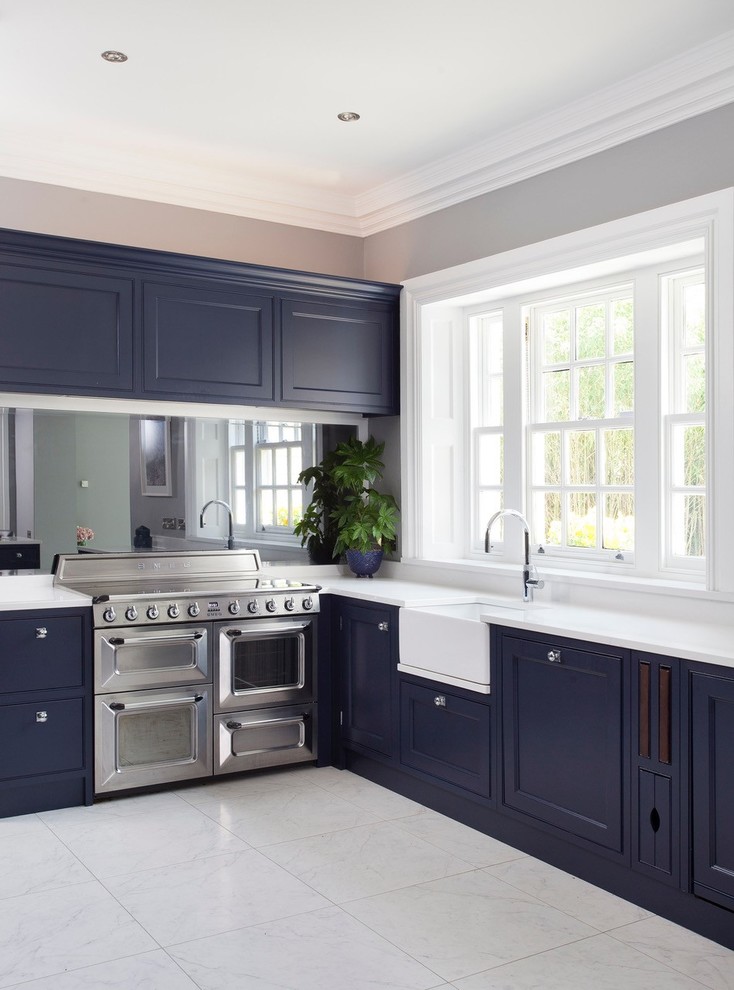 Design ideas for a large traditional u-shaped eat-in kitchen in Dublin with a farmhouse sink, beaded inset cabinets, blue cabinets, quartzite benchtops, metallic splashback, mirror splashback, stainless steel appliances, ceramic floors, with island, blue floor and white benchtop.