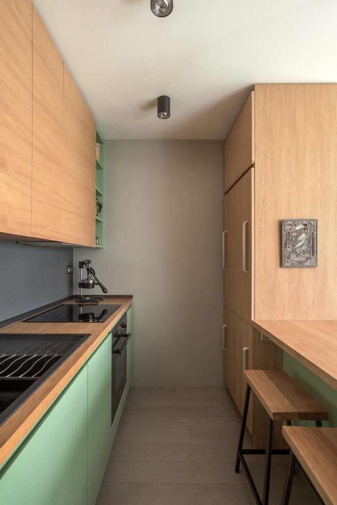 Photo of a small scandinavian galley eat-in kitchen in Paris with a single-bowl sink, beaded inset cabinets, light wood cabinets, wood benchtops, grey splashback, panelled appliances, painted wood floors and grey floor.