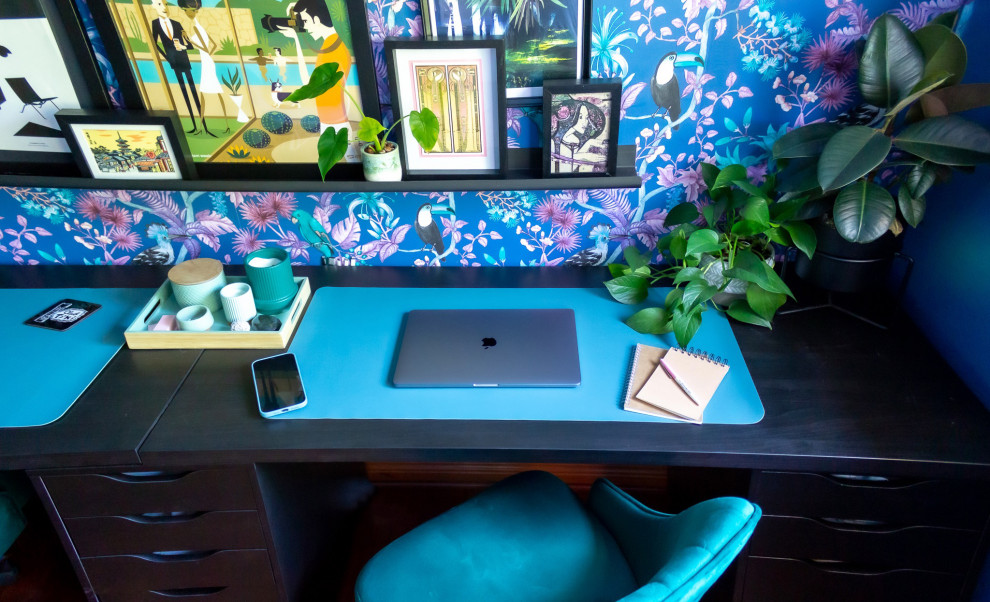 This is an example of a mid-sized tropical craft room in San Diego with blue walls, medium hardwood floors and a freestanding desk.