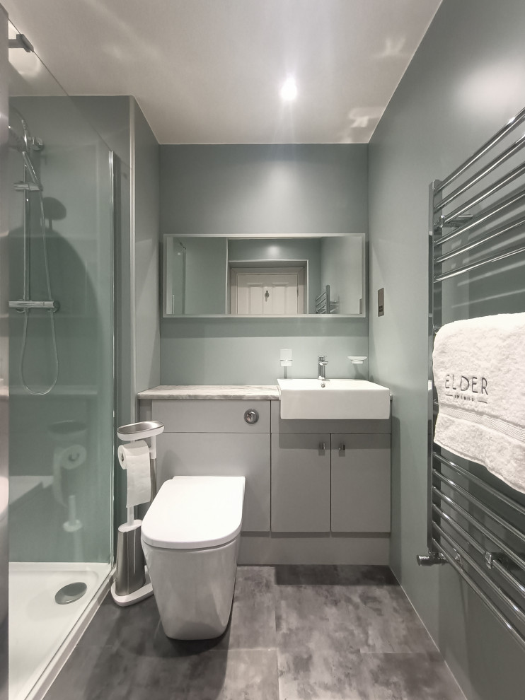 Стильный дизайн: маленькая главная ванная комната в современном стиле с плоскими фасадами, серыми фасадами, открытым душем, унитазом-моноблоком, зеленой плиткой, зелеными стенами, полом из винила, накладной раковиной, столешницей из ламината, серым полом, открытым душем, серой столешницей, акцентной стеной, тумбой под одну раковину, встроенной тумбой, многоуровневым потолком и панелями на части стены для на участке и в саду - последний тренд