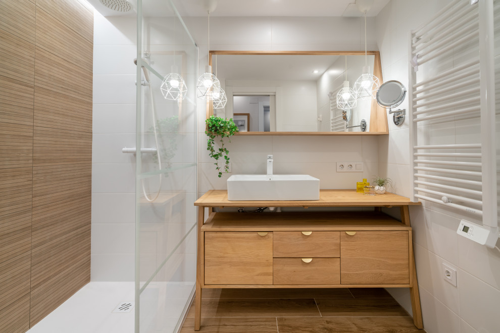 Photo of a mid-sized scandinavian kids wet room bathroom in Other with flat-panel cabinets, brown cabinets, a one-piece toilet, white tile, ceramic tile, brown walls, ceramic floors, a trough sink, wood benchtops, brown floor, brown benchtops, a single vanity, a freestanding vanity and wood walls.