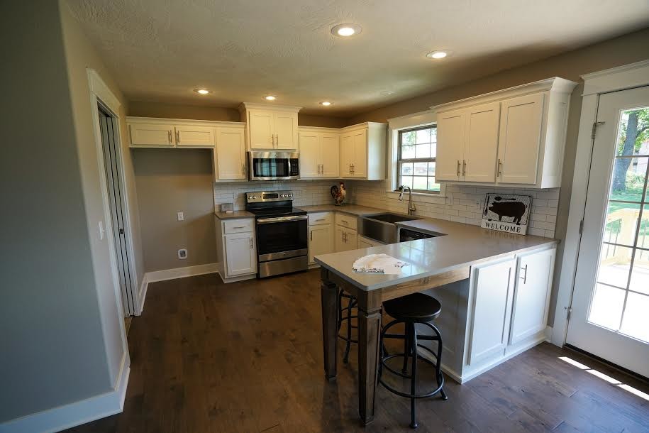 Inspiration for a large transitional u-shaped medium tone wood floor and brown floor eat-in kitchen remodel with a farmhouse sink, shaker cabinets, white cabinets, quartzite countertops, white backsplash, subway tile backsplash, stainless steel appliances and a peninsula