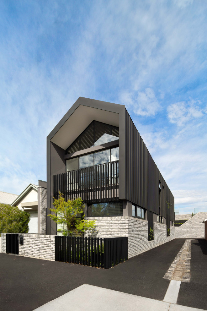 Large modern two-storey brick grey house exterior in Melbourne with a black roof.