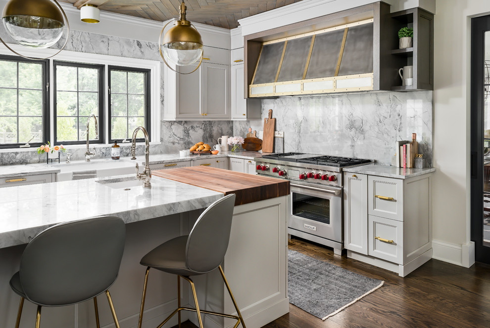 Mid-sized transitional medium tone wood floor and brown floor enclosed kitchen photo in Chicago with a farmhouse sink, recessed-panel cabinets, gray cabinets, quartzite countertops, gray backsplash, stone slab backsplash, paneled appliances, an island and gray countertops