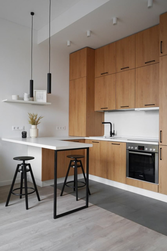 Inspiration for a small scandinavian u-shaped open plan kitchen with an undermount sink, flat-panel cabinets, medium wood cabinets, laminate benchtops, white splashback, black appliances, porcelain floors, no island, grey floor and white benchtop.