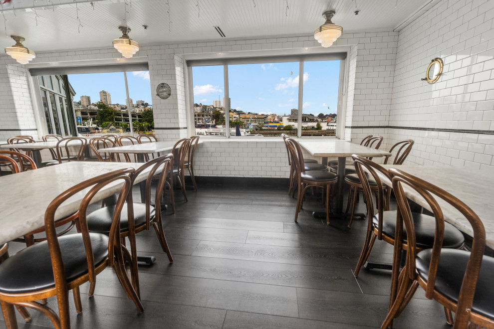 Inspiration for a large beach style open plan dining in San Francisco with white walls, vinyl floors, no fireplace, black floor, recessed and brick walls.
