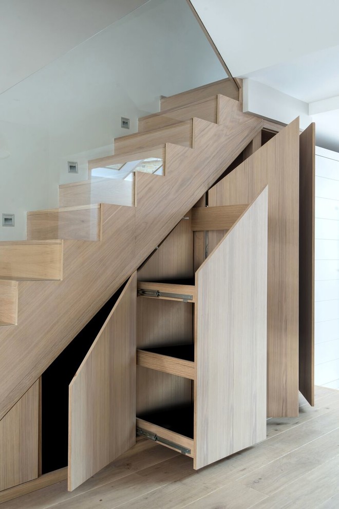 Inspiration for a mid-sized contemporary wood curved staircase in London with glass railing and wood risers.
