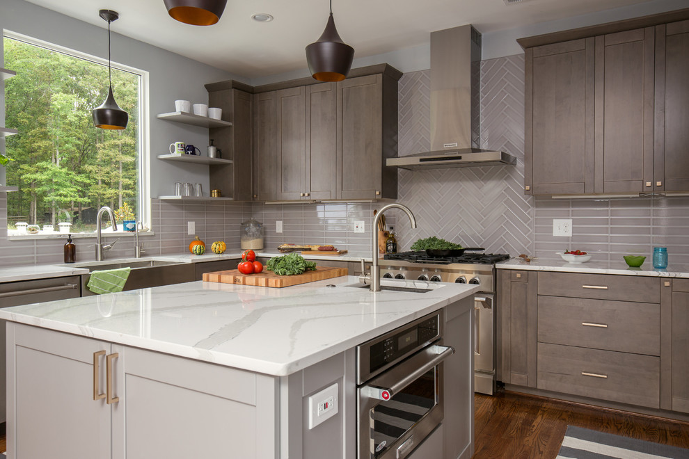 Photo of a large contemporary u-shaped eat-in kitchen in DC Metro with an undermount sink, shaker cabinets, grey cabinets, quartz benchtops, grey splashback, porcelain splashback, stainless steel appliances, medium hardwood floors and with island.