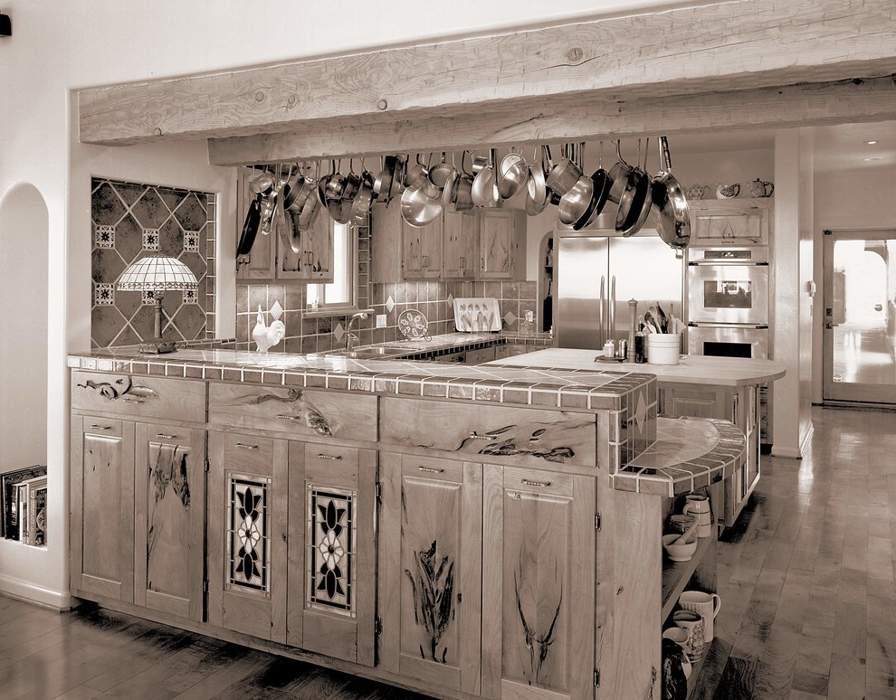 Inspiration for a large u-shaped light wood floor eat-in kitchen remodel in Phoenix with an island, recessed-panel cabinets, medium tone wood cabinets, tile countertops, stone tile backsplash, stainless steel appliances and a drop-in sink