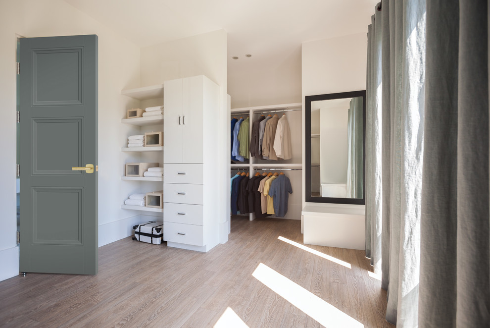 Design ideas for a modern storage and wardrobe in Los Angeles with flat-panel cabinets, white cabinets and light hardwood floors.