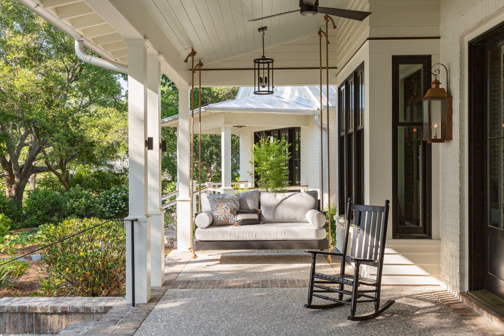 Inspiration for a transitional front yard verandah in Charleston with with columns, a roof extension and mixed railing.