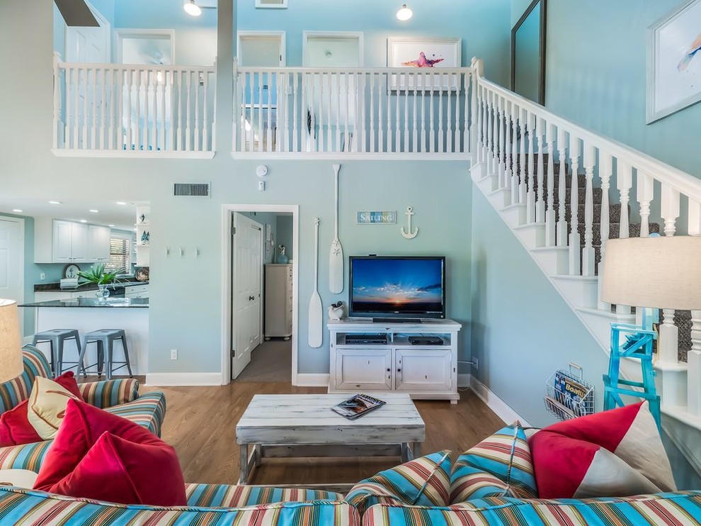 Family room - coastal open concept medium tone wood floor and beige floor family room idea in Tampa with blue walls and a tv stand