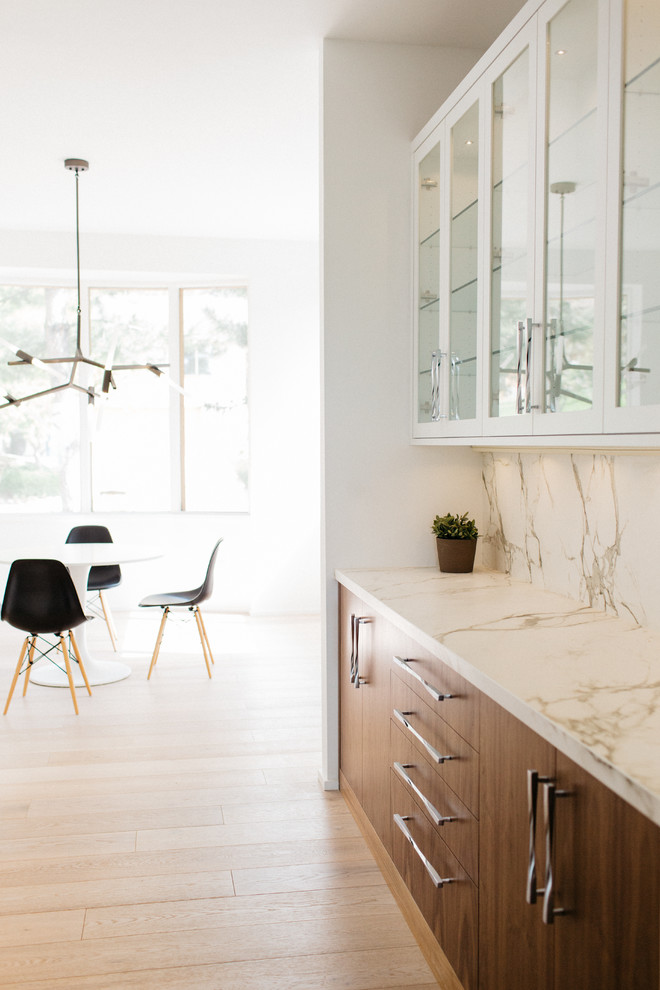 This is an example of a mid-sized modern galley open plan kitchen in Seattle with an undermount sink, flat-panel cabinets, white cabinets, marble benchtops, white splashback, stone slab splashback, panelled appliances, medium hardwood floors and with island.
