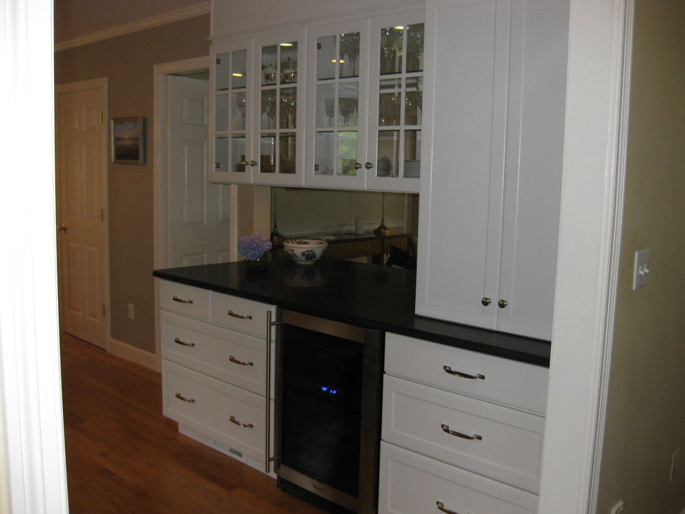 Example of a transitional u-shaped medium tone wood floor eat-in kitchen design in Boston with an undermount sink, recessed-panel cabinets, white cabinets, gray backsplash, subway tile backsplash, stainless steel appliances, an island and black countertops