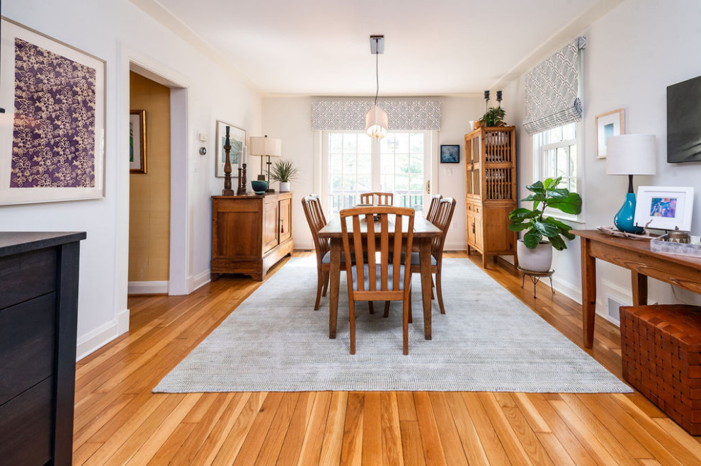 Immagine di una sala da pranzo aperta verso la cucina chic con pareti bianche, pavimento in legno massello medio e pavimento marrone