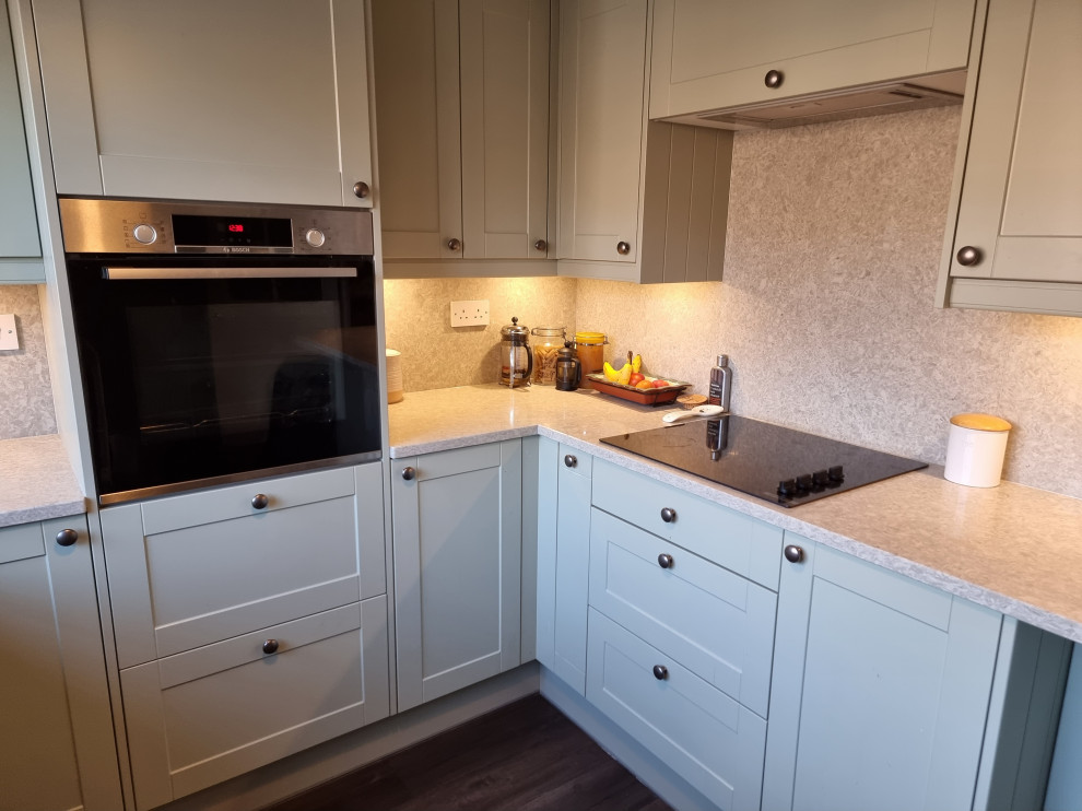 This is an example of a large victorian u-shaped enclosed kitchen in London with a double-bowl sink, shaker cabinets, white cabinets, quartz worktops, multi-coloured splashback, engineered quartz splashback, integrated appliances, lino flooring, black floors, multicoloured worktops and feature lighting.