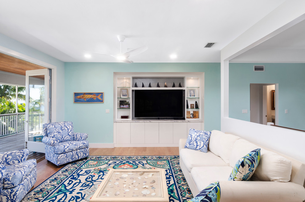 Mid-sized beach style enclosed living room in Miami with blue walls, no fireplace, a built-in media wall, light hardwood floors and beige floor.