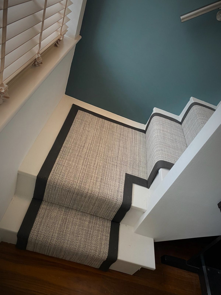 This is an example of a large modern carpeted straight wood railing staircase in Hertfordshire with carpeted risers.