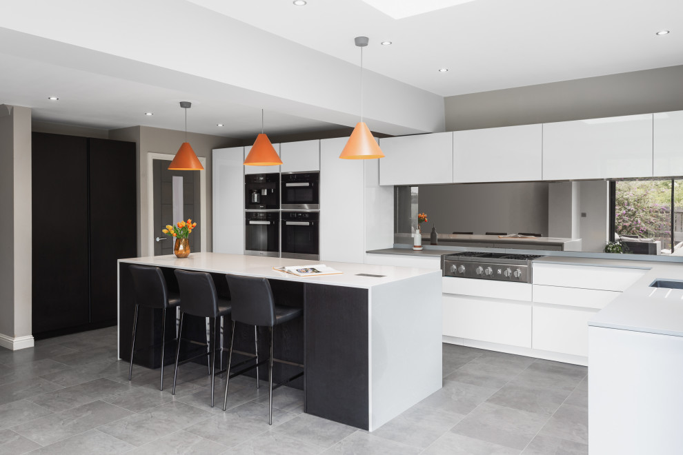 Inspiration for a large contemporary l-shaped kitchen in Other with an undermount sink, flat-panel cabinets, white cabinets, mirror splashback, stainless steel appliances, with island, grey floor and grey benchtop.