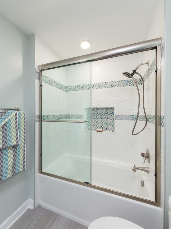Mid-sized contemporary master bathroom in Chicago with flat-panel cabinets, white cabinets, an alcove tub, a shower/bathtub combo, a one-piece toilet, multi-coloured tile, ceramic tile, green walls, medium hardwood floors, an undermount sink and limestone benchtops.