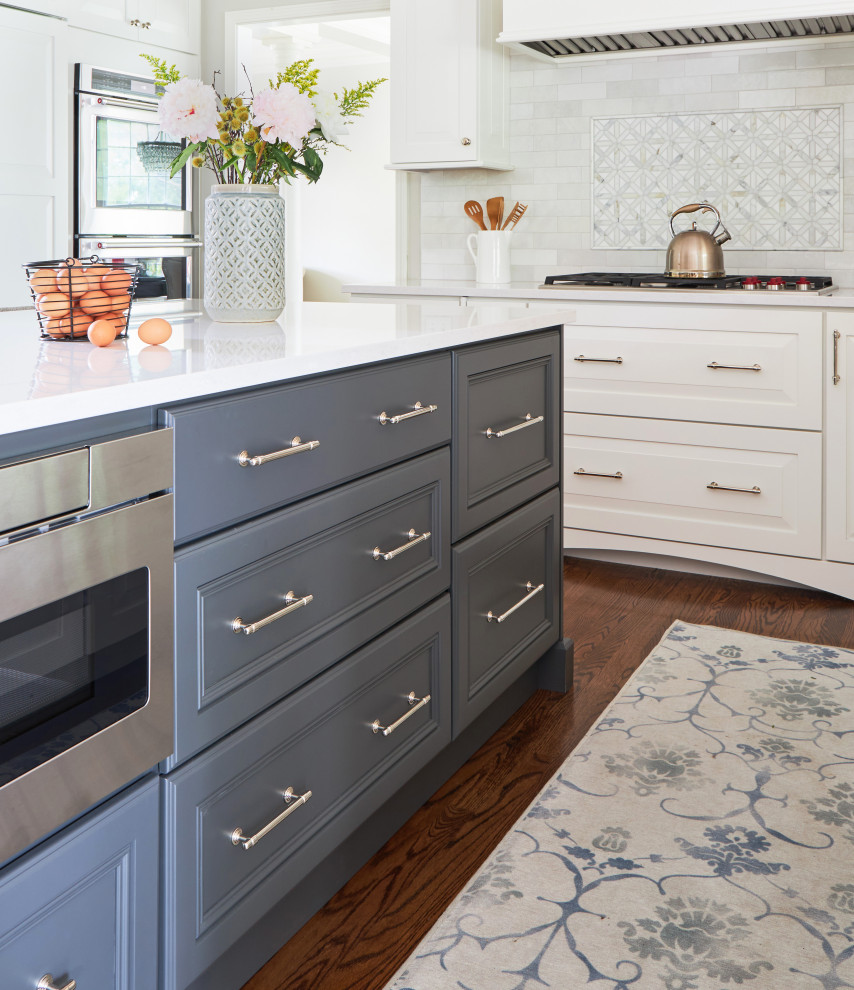 Example of a mid-sized transitional galley medium tone wood floor, brown floor and tray ceiling eat-in kitchen design in Chicago with a farmhouse sink, shaker cabinets, white cabinets, quartzite countertops, white backsplash, subway tile backsplash, white appliances, an island and white countertops