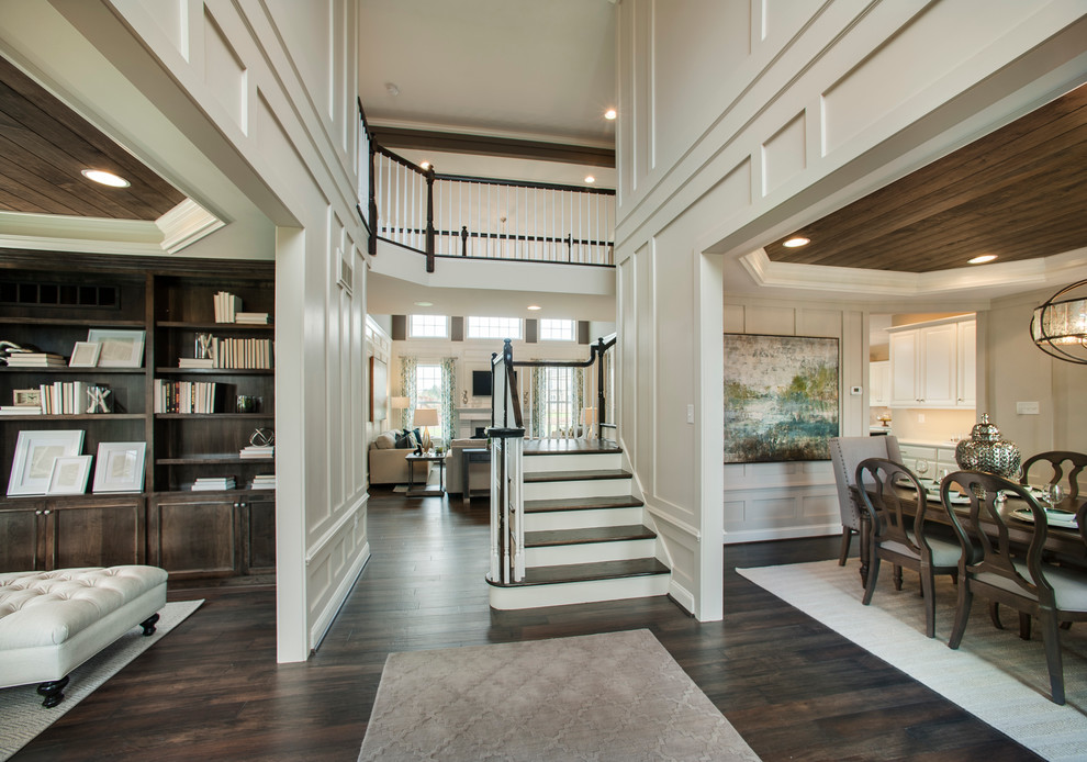 Large transitional entry hall in Philadelphia with white walls, dark hardwood floors and a single front door.