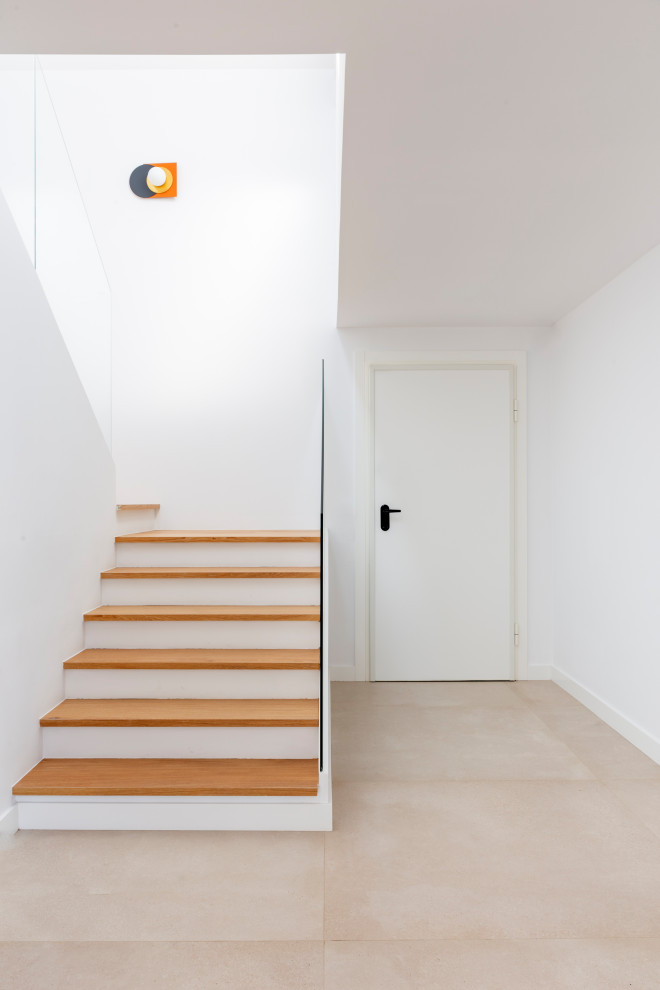 Источник вдохновения для домашнего уюта: п-образная лестница среднего размера в стиле модернизм с деревянными ступенями, стеклянными перилами и любой отделкой стен