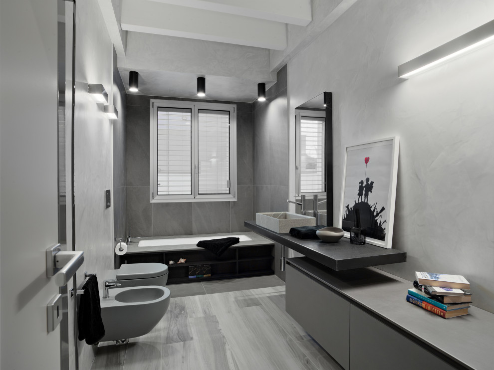 Inspiration for a medium sized contemporary cloakroom in Milan with flat-panel cabinets, grey cabinets, a wall mounted toilet, grey tiles, porcelain tiles, grey walls, porcelain flooring, a vessel sink, laminate worktops, grey floors, a floating vanity unit and exposed beams.