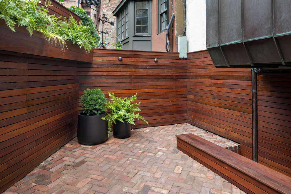 Photo of a small contemporary backyard patio in New York with brick pavers.