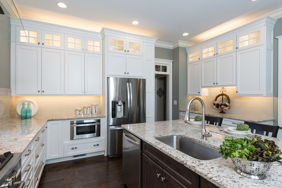 Inspiration for a huge transitional l-shaped dark wood floor and brown floor eat-in kitchen remodel in Atlanta with an undermount sink, recessed-panel cabinets, white cabinets, granite countertops, gray backsplash, porcelain backsplash, stainless steel appliances, an island and white countertops