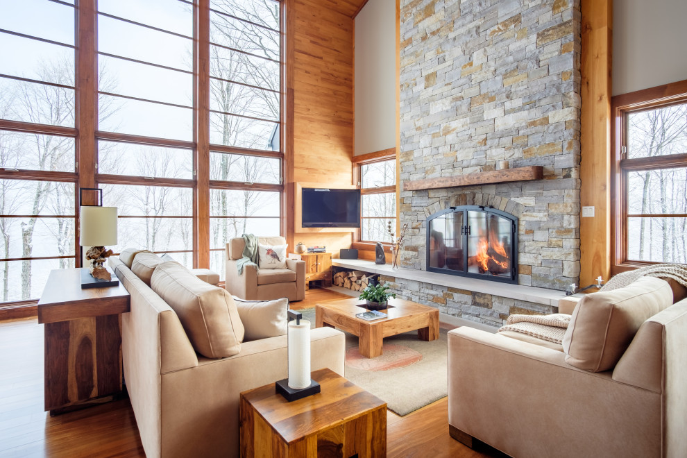 This is an example of a country open concept family room in San Francisco with beige walls, medium hardwood floors, a stone fireplace surround, a wall-mounted tv, a standard fireplace, vaulted and wood walls.