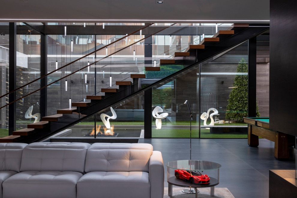 Свежая идея для дизайна: огромная лестница на больцах в стиле модернизм с деревянными ступенями и стеклянными перилами без подступенок - отличное фото интерьера